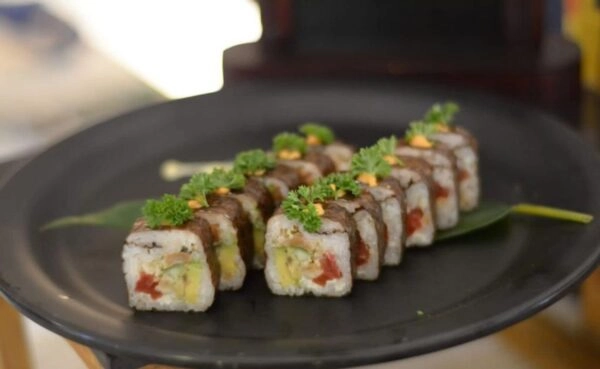 Beautifully plated sushi rolls garnished with fresh herbs served by Plaza Catering's expert catering team in Kerala