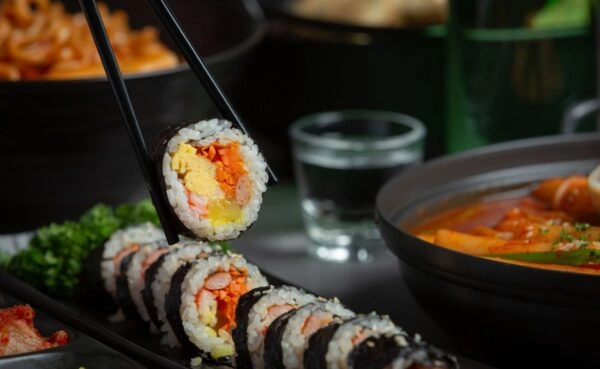 Freshly prepared maki sushi and nigiri sushi held with chopsticks served as part of Plaza Catering's premium live counter catering experience in Kerala