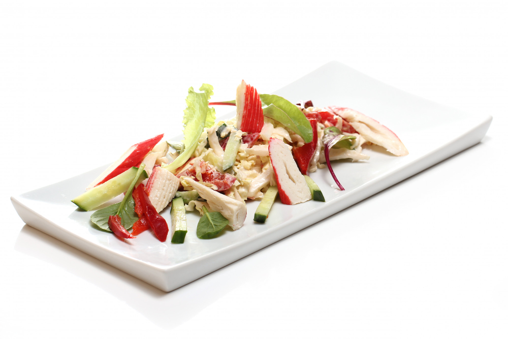 A plate of crab salad with vegetables and lettuce.