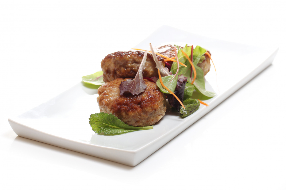 A plate of meat patties with a side salad.